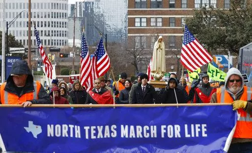 Protesters walk along Jackson St. during the North Texas March for Life, celebrating the passage and court rulings upholding the Texas law known as Senate Bill 8, on Saturday, Jan. 15, 2022, in Dallas. Abortions in Texas fell by 60% in the first month under the most restrictive abortion law in the U.S. in decades. That's according to the fist figures released by Texas health officials since the law known as Senate Bill 8 took effect in September. (Shafkat Anowar/The Dallas Morning News via AP)