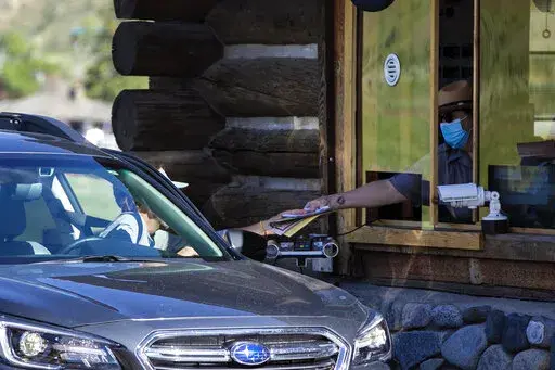 In this Monday, June 1, 2020 photo, a gate attendant at the North Entrance deals with visitors as the Montana entrances to Yellowstone National Park, in Wyoming, reopened after being closed due to COVID-19. On Friday, Dec. 23, 2022, The Associated Press reported on stories circulating online incorrectly claiming Yellowstone National Park officials have “closed down the park” due to a rising “volcanic uplift.” (Ryan Berry/Bozeman Daily Chronicle via AP, File)/Bozeman Daily Chronicle via A