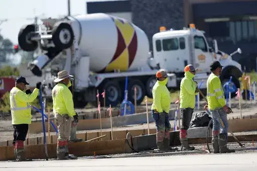Construction crew members wait to pour concrete in a parking lot on Sept. 4, 2024, in Waukee, Iowa. (AP Photo/Charlie Neibergall, File)