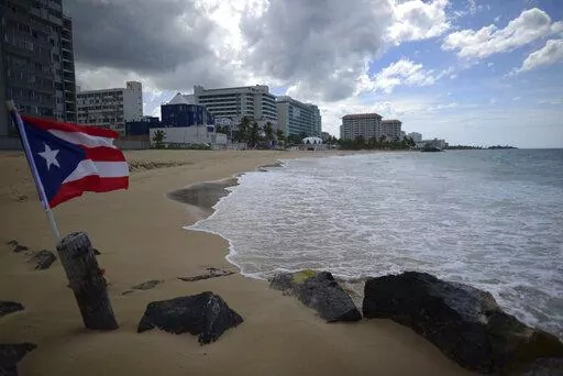 A Puerto Rican flag flies on an empty beach at Ocean Park, in San Juan, Puerto Rico, Thursday, May 21, 2020.  Puerto Rico’s nearly five-year bankruptcy battle was resolved Tuesday, Jan. 18, 2022, after a federal judge signed a plan that slashes the U.S. territory’s public debt load as part of a restructuring and allows the government to start repaying creditors. (AP Photo/Carlos Giusti, File)