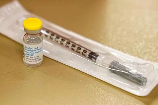 A vial containing the monkeypox vaccine and a syringe is set on the table at a vaccination clinic run by the Mecklenburg County Public Health Department in Charlotte, N.C., Saturday, Aug. 20, 2022. At-risk people who received just one dose of the monkeypox vaccine appeared to be significantly less likely to get sick from the virus, public health officials announced Wednesday, even as they urged a second dose for full protection. (AP Photo/Nell Redmond, File)