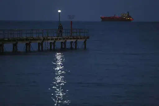 A man walks on a dock as a ship seen in the background in southern port city of Limassol, Cyprus, Friday, Feb. 23, 2018. Cyprus is working out with partners in the European Union and the Middle East the logistics to establish a sea corridor to deliver a stream of vital humanitarian aid to Gaza from the island’s main port of Limassol once the situation on the ground permits it. (AP Photo/Petros Karadjias, File)