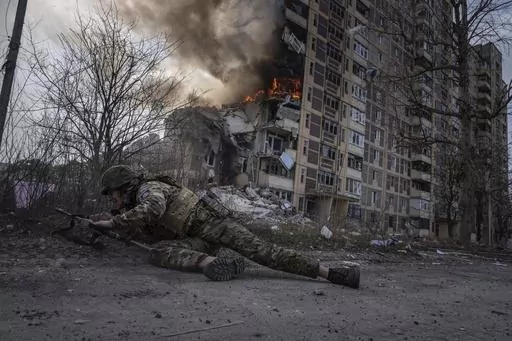 A Ukrainian police officer takes cover in front of a burning building in Avdiivka, Ukraine, Friday, March 17, 2023. The second year of Ukraine’s fight against Russia’s full-scale invasion brought no respite for Ukrainian soldiers or civilians. Associated Press photographers documented the past 12 months of death and destruction, agony and grief — as well as the glimpses of joy — that are staples of life during war. (AP Photo/Evgeniy Maloletka)