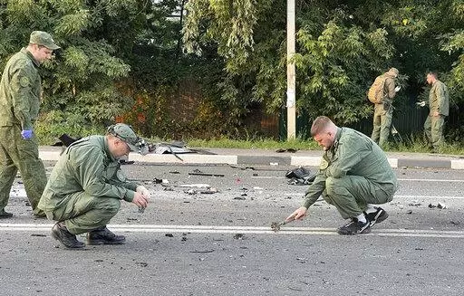In this handout photo taken from video released by Investigative Committee of Russia on Sunday, Aug. 21, 2022, investigators work on the site of explosion of a car driven by Daria Dugina outside Moscow. Daria Dugina, the daughter of Alexander Dugin, the Russian nationalist ideologist often called "Putin's brain", was killed when her car exploded on the outskirts of Moscow, officials said Sunday. The Investigate Committee branch for the Moscow region said the Saturday night blast was caused by a 