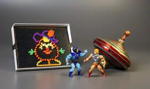 This undated photo provided by The Strong Museum shows the three toys inducted into the National Toy Hall of Fame on Nov. 10, 2022, in Rochester, N.Y. Masters of the Universe, Lite-Brite and the top were chosen from among 12 finalists for the annual honor, which recognizes toys that have inspired creative play and lasting popularity. (Courtesy of The Strong Museum via AP)