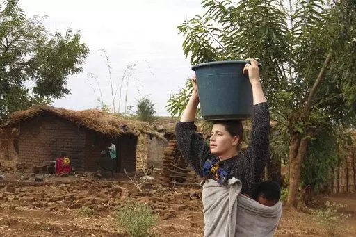 Cameron Beach, carries a carries a bucket of water on her head collected from a communal borehole in Dedza, near Lilongwe, Malawi, on July 23, 2021. Beach, a former Peace Corps volunteer, is living in rural Malawi teaching English at a rural high school where she had been sent by the United States government 18-months before COVID-19 began sweeping the world. The Peace Corps says it'll start sending volunteers overseas again in mid-March after it evacuated them from posts around the world two ye