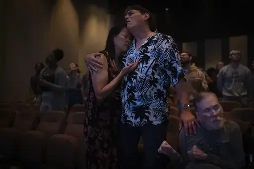 Lesley Dzik, left, and her husband, Matt, embrace each other while praying with Richard Wellbank at The Vineyard Church in Urbana, Ill., Sunday, Sept. 22, 2024. Lesley, a Republican, and Matt, a Democrat, have navigated issues common to so many marriages, from parenting to money. But politics? That's complicated. (AP Photo/David Goldman)