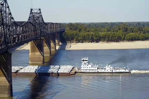 Low-water restrictions on the barge loads make for cautious navigation through the Mississippi River as evidenced by this tow passing under a Mississippi River bridge in Vicksburg, Tuesday, Oct. 11, 2022. The unusually low water level in the lower Mississippi River has caused some barges to get stuck in the muddy river bottom, resulting in delays. (AP Photo/Rogelio V. Solis)