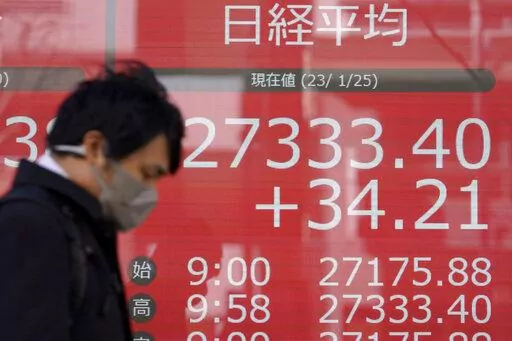 A person wearing a protective mask walks in front of an electronic stock board showing Japan's Nikkei 225 index at a securities firm Wednesday, Jan. 25, 2023, in Tokyo. Asian shares were mixed Wednesday after Wall Street indexes finished little changed as investors awaited earnings results from major global companies. (AP Photo/Eugene Hoshiko)