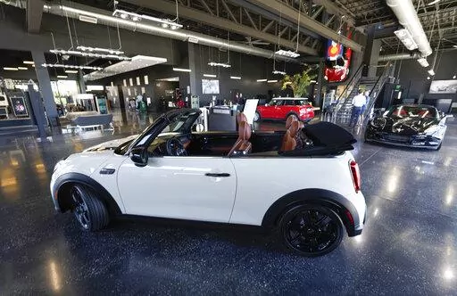 A sales associate talks with a prospective buyer of a Cooper SE electric vehicle on the showroom floor of a Mini dealership July 7, 2022, in Highlands Ranch, Colo. The surprise deal by Senate Democrats on a pared-down bill to support families, boost infrastructure and fight climate change is likely to jump start sales of electric vehicles. (AP Photo/David Zalubowski, File)