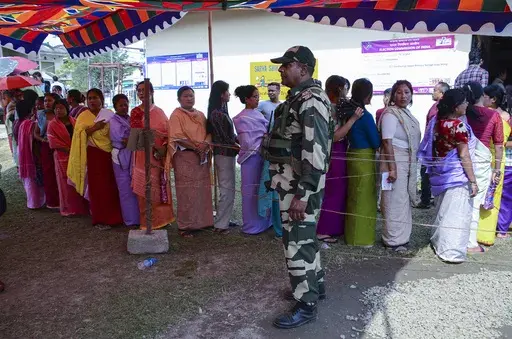A Border Security Force soldier stands guard as women queue up to vote during a re-polling in Imphal West District, Manipur, India, Monday, April 22, 2024. Voters at some polling places in this northeastern state went back to the polls amid tight security on Monday after violence disrupted the vote last week. (AP Photo/Bullu Raj)