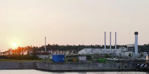 The sun rises behind the landfall facility of the Nord Stream 1 Baltic Sea pipeline and the transfer station of the OPAL gas pipeline, the Baltic Sea Pipeline Link, in Lubmin, Germany, Thursday, July 21, 2022. The operator of the major pipeline from Russia to Europe says natural gas has started flowing again after a 10-day shutdown for maintenance. (AP Photo/Markus Schreiber)