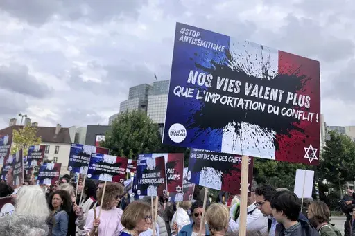 People gather against anti semitism, one carrying a placard reading "our lives worth more that an imported conflict" Thursday, June 20, 2024 in Paris. The alleged rape of a 12-year-old Jewish girl in a suspected antisemitic attack has sent shockwaves throughout France, and thrust concerns about antisemitism to the forefront of campaigning for the country's legislative elections. (AP Photo/Oleg Cetinic)