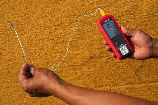 Vivek Shandas, a professor of climate adaptation at Portland State University, takes a temperature reading of almost 106 degrees in downtown Portland, Ore., on Aug. 12, 2021. On Thursday, Jan. 13, 2022, NASA and the National Oceanic and Atmospheric Administration released measurements showing 2021 was the sixth hottest year on record globally, part of a long-term warming trend. (AP Photo/Nathan Howard, File)