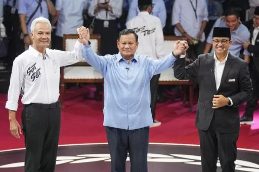 Presidential candidates, from left, Ganjar Pranowo, Prabowo Subianto and Anies Baswedan holds hands as they pose for photographers after the first presidential candidates' debate in Jakarta, Indonesia, Tuesday, Dec. 12, 2023. Indonesia, the world's third-largest democracy, will open its polls on Wednesday to nearly 205 million eligible voters in presidential and legislative elections, the fifth since Southeast Asia's largest economy began democratic reforms in 1998. (AP Photo/Tatan Syuflana, Fil