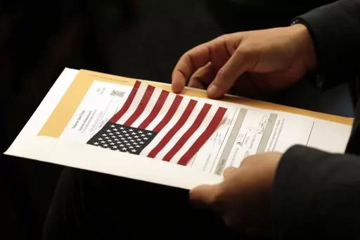 Abdullah Omar, from Iraq, holds his information packet and an American flag during a naturalization ceremony on Jan. 17, 2020, in Cleveland. Two decades after the U.S. invasion of Iraq, thousands of Iraqis are still trying to emigrate to the United States. An estimated 164,000 Iraqis have already found homes in America since the 2003 invasion. But many are still waiting. (AP Photo/Tony Dejak, File)