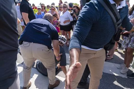 President Joe Biden is helped by U.S. Secret Service agents after he fell trying to get off his bike to greet a crowd on a trail at Gordons Pond in Rehoboth Beach, Del., Saturday, June 18, 2022.  On Friday, June 24, The Associated Press reported on stories circulating online incorrectly claiming the Atlantic published an article with the headline, “The Heroism of Biden’s Bike Fall” after Biden fell on Saturday as he tried to dismount his bicycle. (AP Photo/Manuel Balce Ceneta, File)