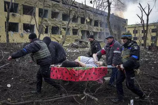 Ukrainian emergency employees and volunteers carry an injured pregnant woman from the maternity hospital that was damaged by shelling in Mariupol, Ukraine, Wednesday, March 9, 2022. A Russian attack has severely damaged the maternity hospital in the besieged port city of Mariupol, Ukrainian officials say. (AP Photo/Evgeniy Maloletka, File)