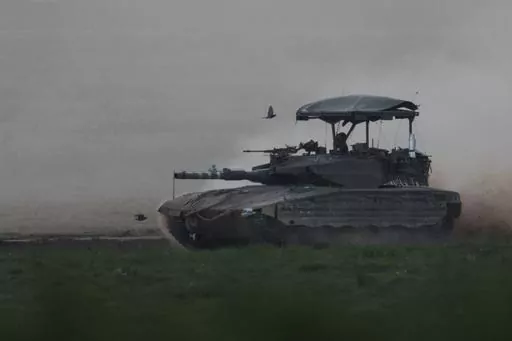 Israeli soldier moves on the top of a tank near the Israeli-Gaza border, as seen from southern Israel, Thursday, Feb. 15, 2024. (AP Photo/Leo Correa)