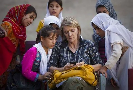 In this Saturday, Oct. 1, 2011 file photo, Associated Press Special Regional Correspondent for Afghanistan and Pakistan Kathy Gannon sits with girls at a school in Kandahar, Afghanistan. A Kabul court announced Wednesday, July 23, 2014 that the Afghan police officer charged with killing Associated Press photographer Anja Niedringhaus and wounding veteran AP correspondent Kathy Gannon has been convicted and sentenced to death.(AP Photo/Anja Niedringhaus, File)