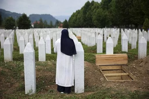 A woman prays near a grave of a family member in the Memorial centre in Potocari, Bosnia, Friday, July 8, 2022. After surviving the 1995 Srebrenica massacre in which over 8,000 of their male relatives were killed, women from the small town in eastern Bosnia dedicated the remaining years of their lives to the re-telling of their trauma to the World, honoring the victims and bringing those responsible for  the killings to justice. (AP Photo/Armin Durgut)