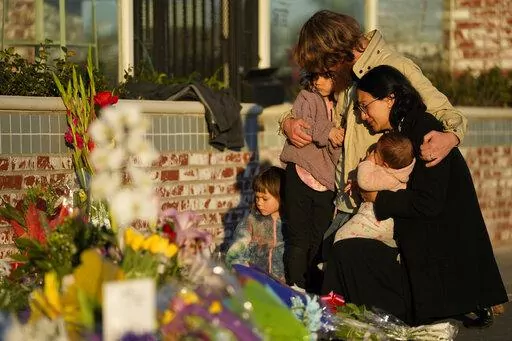 A family gathers at a memorial outside the Star Ballroom Dance Studio, the site of a mass shooting, on Tuesday, Jan. 24, 2023, in Monterey Park, Calif. In the course of 48 hours, two gunmen went on shooting rampages at both ends of California that left 18 dead and 10 wounded. (AP Photo/Ashley Landis, File)