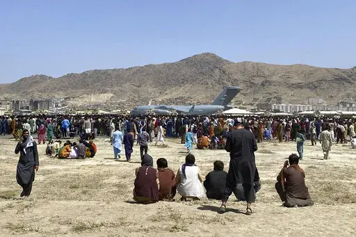 Hundreds of people gather near a U.S. Air Force C-17 transport plane at the perimeter of the international airport in Kabul, Afghanistan, Aug. 16, 2021. An Afghan couple who arrived in the U.S. as refugees are suing a U.S. Marine and his wife for allegedly abducting their baby. (AP Photo/Shekib Rahmani, File)