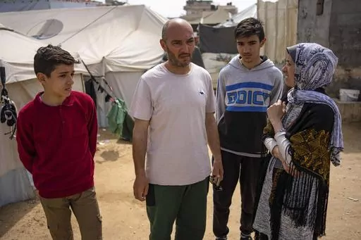Heba al-Haddad, right, and her family displaced from Gaza City, stand in a makeshift tent camp in Rafah, southern Gaza, Friday, March 29, 2024. Al-Haddad was forced out of her home in Gaza City on March 21 when Israeli troops stormed her apartment and ordered her and her family to leave for the south. Amid fighting that has engulfed the area since Israel raided Shifa Hospital, witnesses say troops have been pushing residents out of nearby neighbourhoods. (AP Photo/Fatima Shbair)