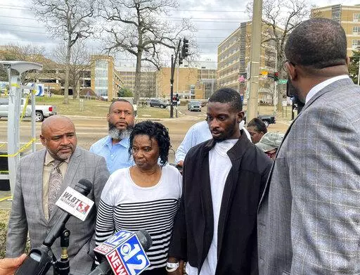 Michael Jenkins, second from right, stand with his mother, Mary Jenkins, center, and their attorneys at a news conference Wednesday, Feb. 15. 2023, in Jackson, Miss., following his release from the hospital three weeks after being shot by sheriff's deputies. The Justice Department says it has opened a civil rights investigation into the Rankin County Sheriff's Office after its deputies wounded Jenkins during a drug raid on Jan. 24. Jenkins says he was beaten and shot in the mouth unjustifiably. 