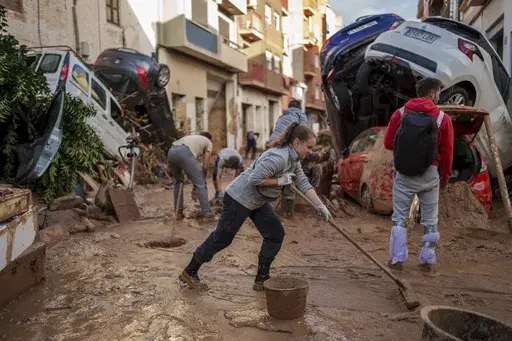 People clean the street of mud in an area affected by floods in Paiporta, a town in the region of Valencia, Spain, Saturday, Nov. 2, 2024. (AP Photo/Manu Fernandez)