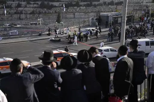 People look at Israeli police officers and volunteers from the Zaka rescue service work at the shooting attack in Jerusalem, Thursday, Nov. 30, 2023. The shooting death of an Israeli man who raced to confront Palestinian attackers has raised questions about the use of excessive force among Israeli security forces and the public. The man's shooting mirrors previous incidents where Israeli security forces or civilians have opened fire on attackers who no longer appear to pose a threat or on suspec