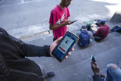 Venezuelan migrant Yender Romero shows the U.S. Customs and Border Protection (CBP) One app on his cell phone, which he said he used to apply for asylum in the U.S. and is waiting on an answer, at a migrant tent camp outside La Soledad church in Mexico City, Monday, Jan. 20, 2025, the inauguration day of U.S. President Donald Trump. (AP Photo/Fernando Llano, File)