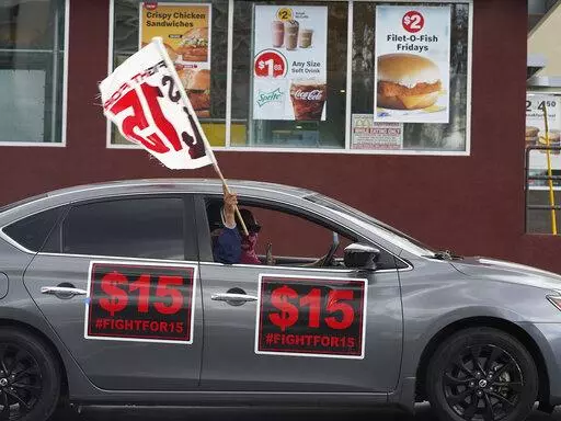 FILE - Fast-food workers drive though a McDonald's restaurant demanding a for a $15 hourly minimum wage in East Los Angeles Friday, March 12, 2021. Minimum wage increases, animal protections, police accountability, cutting and increasing taxes are all part of a series of new laws taking effect across the country on Saturday, the first day of 2022. (AP Photo/Damian Dovarganes, File)