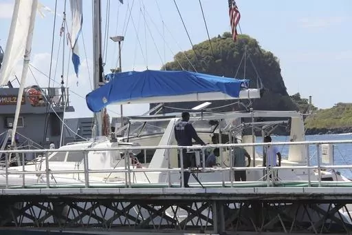 Investigators from Grenada and St. Vincent and the Grenadines stand aboard the yacht "Simplicity", that they say was hijacked by 3 escaped prisoners with two people aboard, now anchored at the St. Vincent and the Grenadines Coastguard Service Calliaqua Base, in Calliaqua, St. Vincent, Friday, Feb. 23, 2024. Authorities in the eastern Caribbean said they were trying to locate two people believed to be U.S. citizens who were aboard the yacht that was hijacked by the three escaped prisoners from Gr