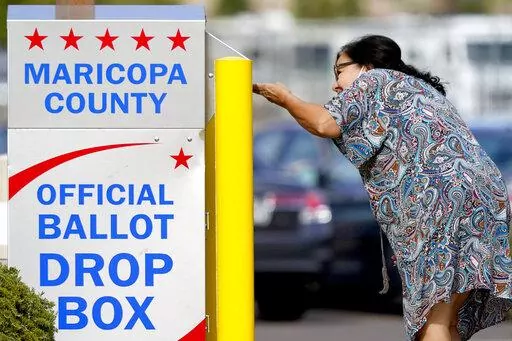 A voter drops off her ballot at a drop box, Nov. 7, 2022, in Mesa, Ariz. Fears of aggressive poll watchers sowing chaos at polling stations or conservative groups trying to intimidate votes didn't materialize on Election Day as many election officials and voting rights experts had feared. Voting proceeded smoothly across most of the U.S., with a few exceptions of scattered disruptions. (AP Photo/Matt York, File)