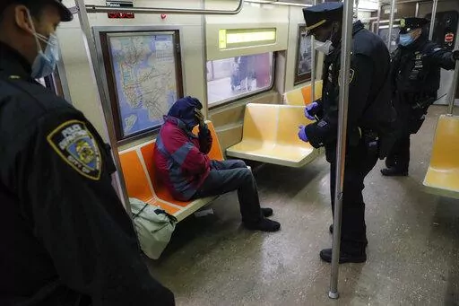 New York Police Department officers wake up sleeping passengers and direct them to the exits at the 207th Street station on the A train, Thursday, April 30, 2020, in the Manhattan borough of New York. In New York City's latest effort to address a mental health crisis on its streets and subways, Mayor Eric Adams announced Tuesday, Nov. 29, 2022, that authorities would more aggressively intervene to help people in need of treatment, saying there was "a moral obligation" to do so, even if it means 