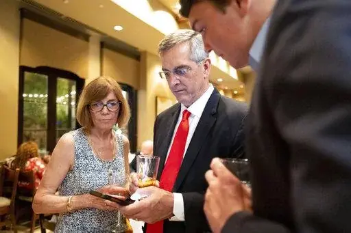 Incumbent Georgia Secretary of State Brad Raffensperger, checks returns with supporters during an election night party Tuesday evening, May 24, 2022, at a small restaurant in Peachtree Corners, Ga. (AP Photo/Ben Gray)