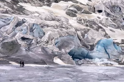 Team members of ETH (Swiss Federal Institute of Technology) glaciologist and head of the Swiss measurement network 'Glamos', Matthias Huss, arrive at the Rhone Glacier partially covered near Goms, Switzerland, June 16, 2023. The U.N. weather agency is reporting that glaciers shrank more than ever from 2011 and 2020, as it released its latest stark report about the fallout on the planet from climate change. (AP Photo/Matthias Schrader, File)
