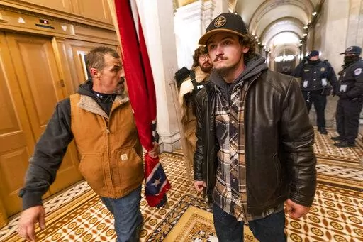 Insurrectionists loyal to President Donald Trump, including Kevin Seefried, left, walk on a hallway after a confrontation with Capitol Police officers outside the Senate Chamber inside the Capitol, Jan. 6, 2021 in Washington. A federal trial is scheduled to start on Monday, June 13, for Seefried and his son Hunter who have been charged with storming the U.S. Capitol together. (AP Photo/Manuel Balce Ceneta, File)