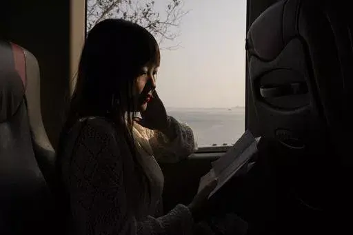 Emilia Wong catches up on reading letters from activist and partner Ventus Lau on her way back after visiting him at prison, in Hong Kong, Monday, March 25, 2024. For decades, Hong Kong's activists have been fighting for democracy. But a national security law imposed by Beijing in 2020 has dramatically changed their lives. In the city's biggest national security case, 47 democracy advocates were charged in 2021 over their roles in an unofficial primary election. (AP Photo/Louise Delmotte)